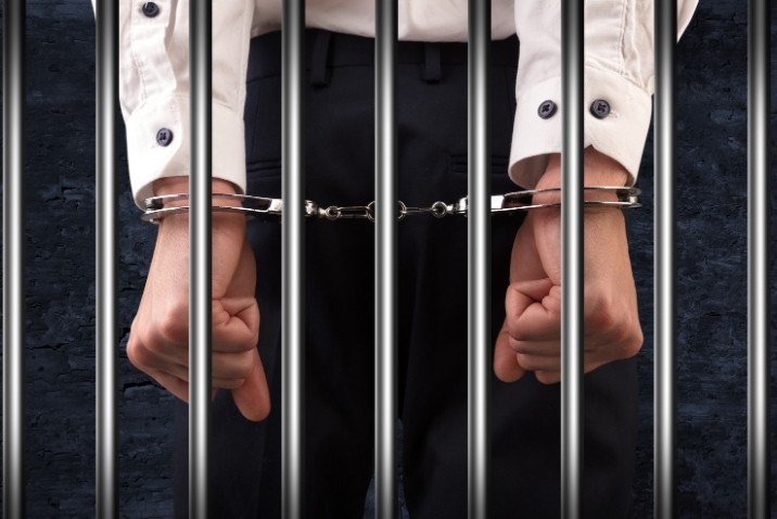 hands with handcuffs and jail bars in its back