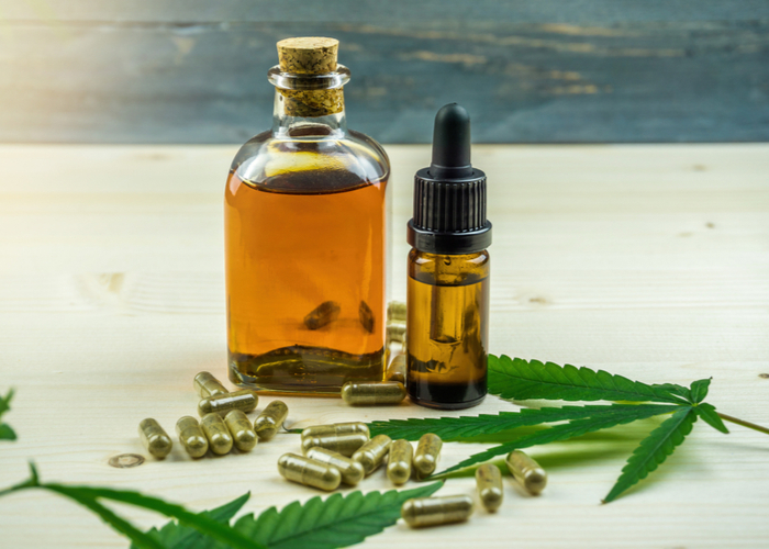 CBD Cannabidiol capsules and cannabis oil on wooden backdrop