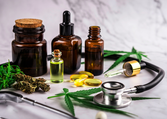 Assorted cannabis products, pills and cbd oil over medical prescription sheet